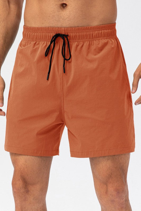 Orange swim shorts with a drawstring on a white background