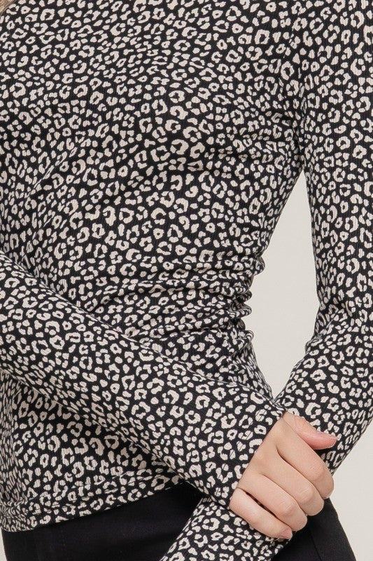 Close-up of a black and white leopard print long-sleeve top with a blurred background.