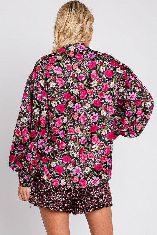 Person wearing a floral blouse and shorts on a plain background