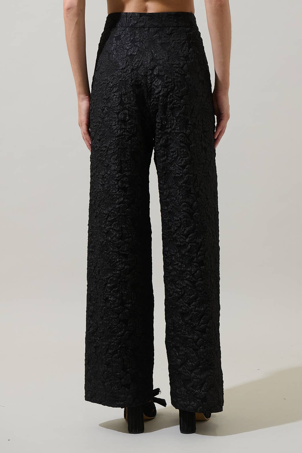 Black lace pants worn by a person on a plain background
