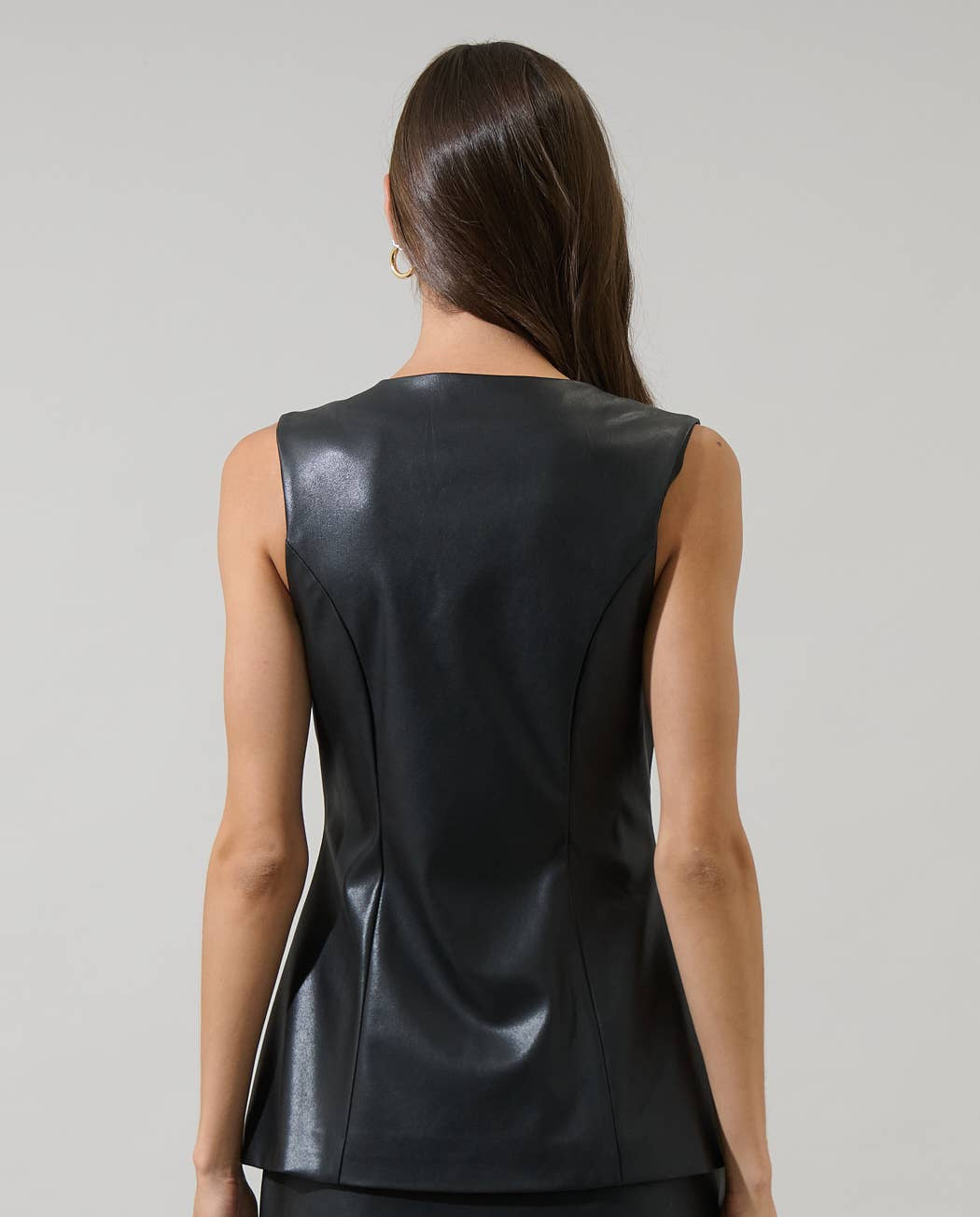 Black leather sleeveless top and skirt worn by a model on a gray background