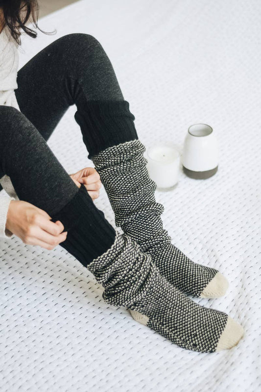 Person wearing black leggings and patterned socks on a white surface