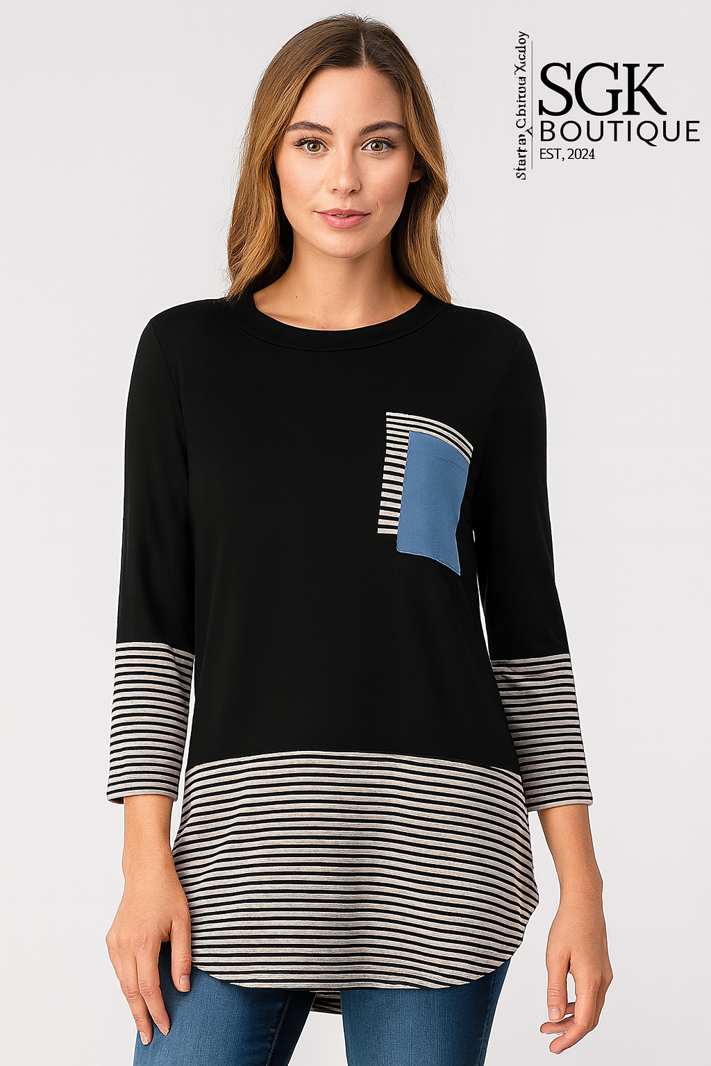 Woman wearing a black and striped long-sleeve top with a blue pocket, standing against a white background. SGK Boutique logo visible.