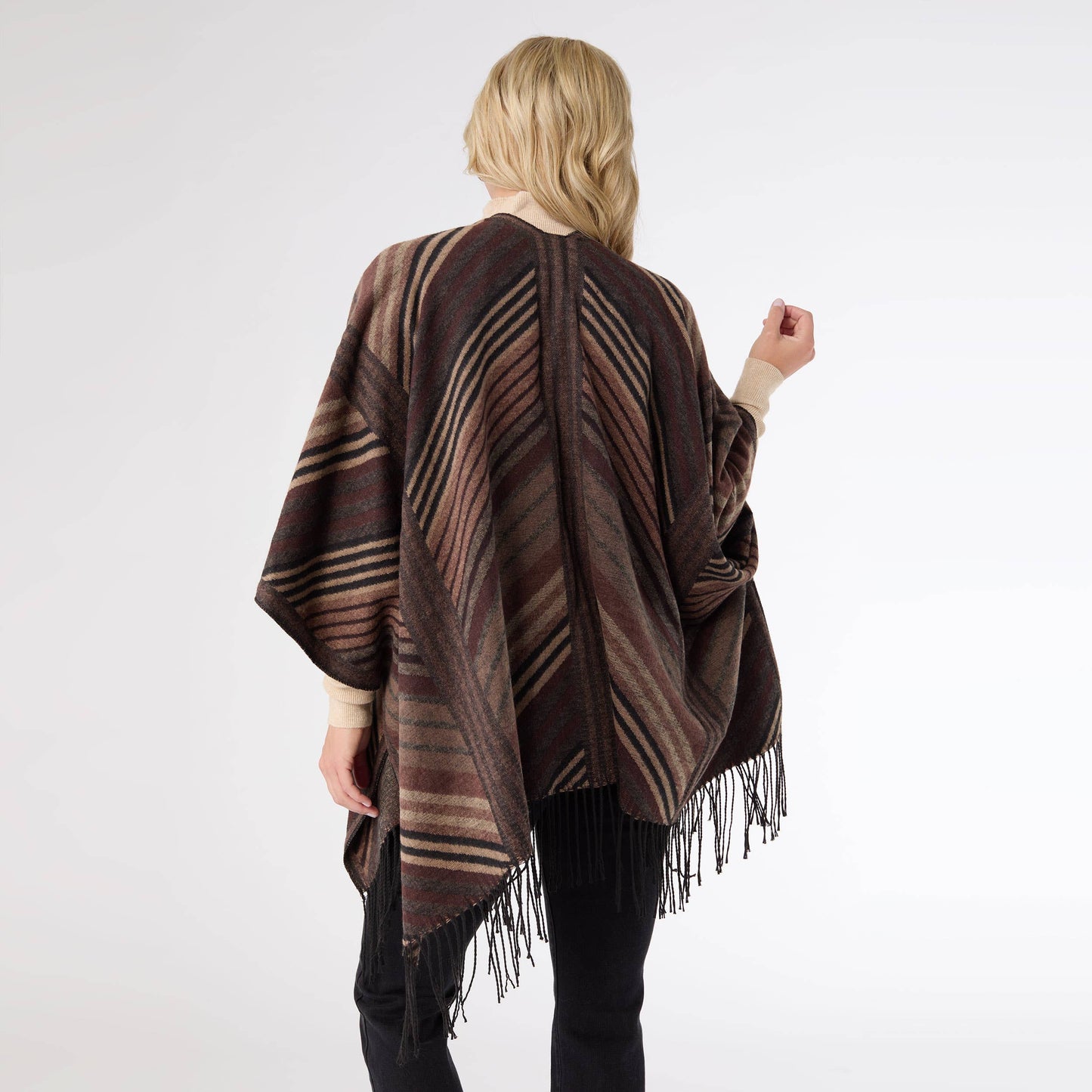 Woman wearing a brown striped poncho with fringe on a white background