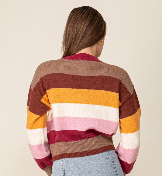 Person wearing a colorful striped sweater and denim skirt on a beige background