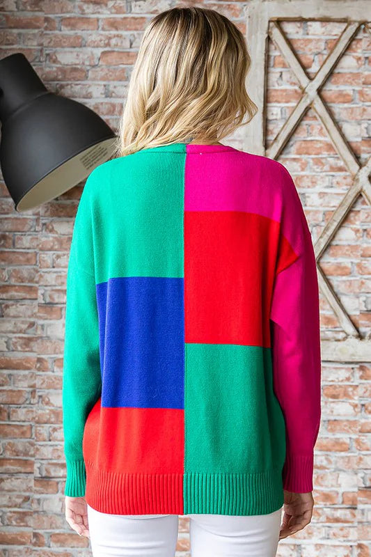Person wearing a colorful checkered sweater against a brick wall.