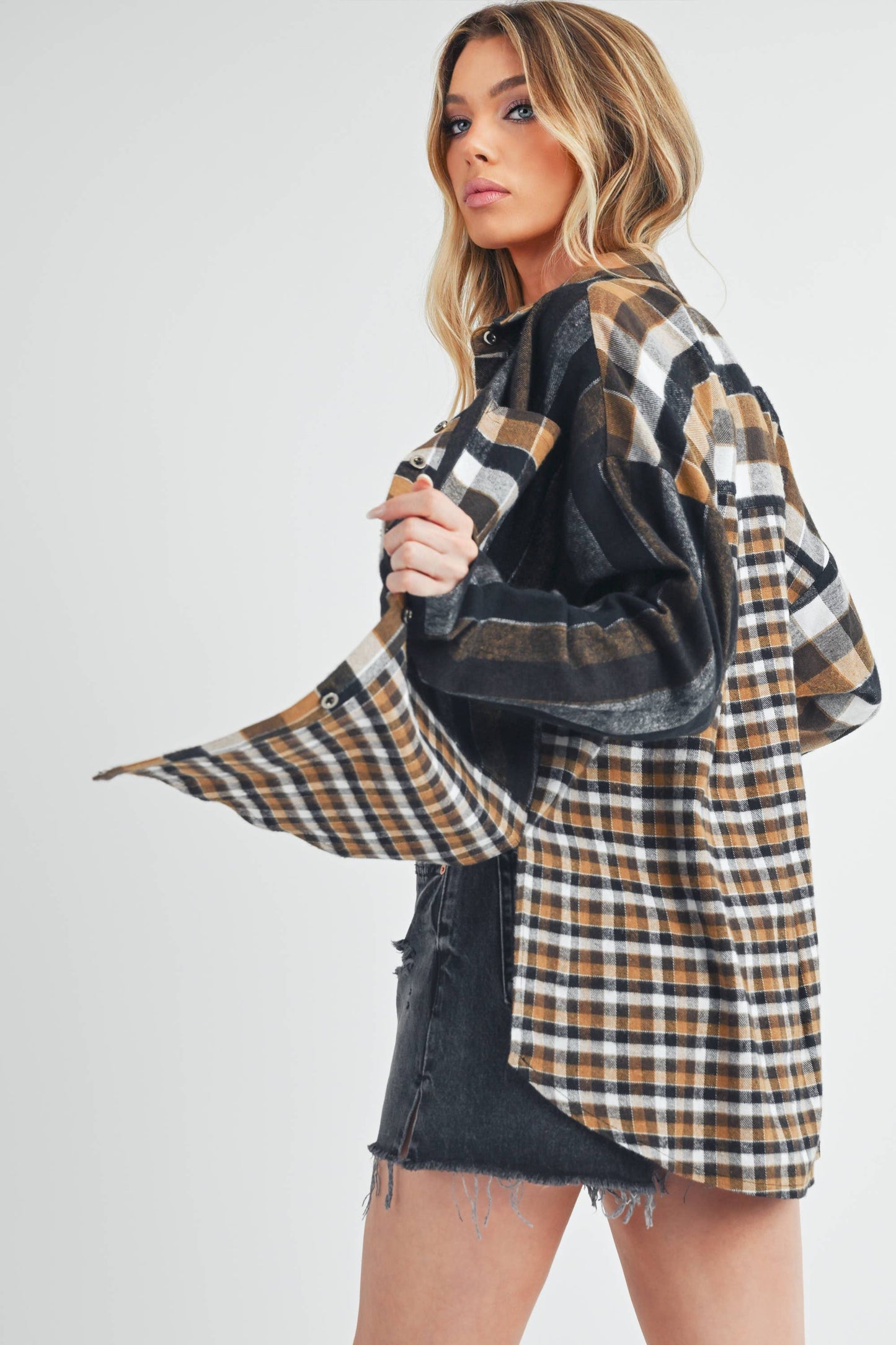 Woman wearing a plaid shirt over a black top with a white background