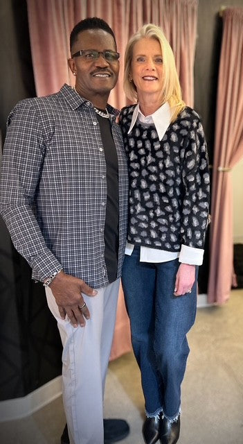 Two people standing together in a room with pink curtains.
