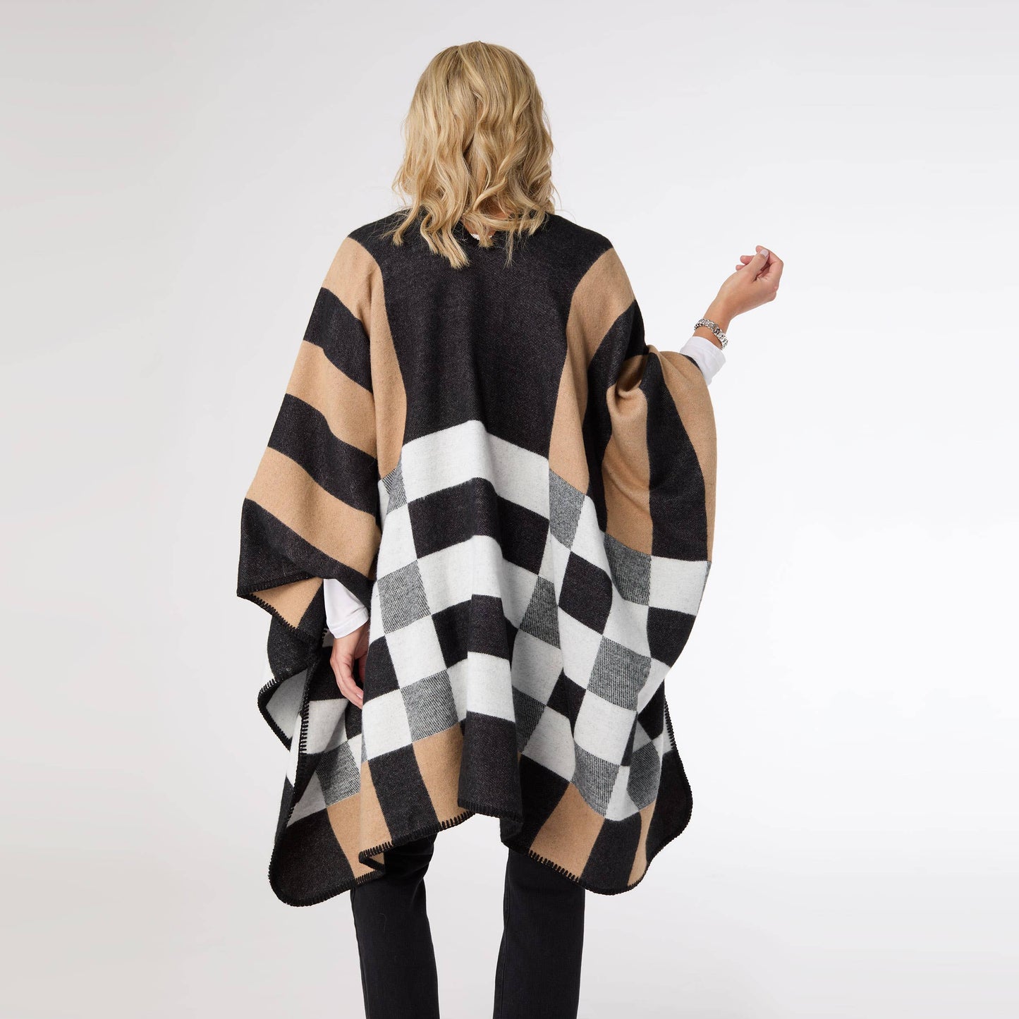 Person wearing a black, beige, and white checkered poncho on a white background