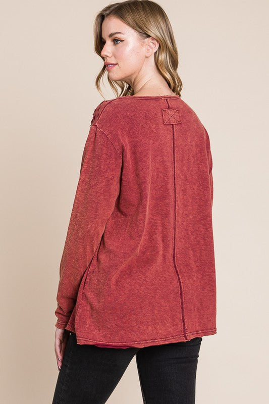 Woman wearing a red long-sleeve top against a beige background