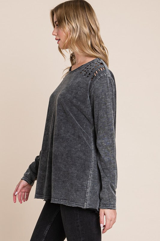 Woman wearing a gray distressed long-sleeve top on a beige background