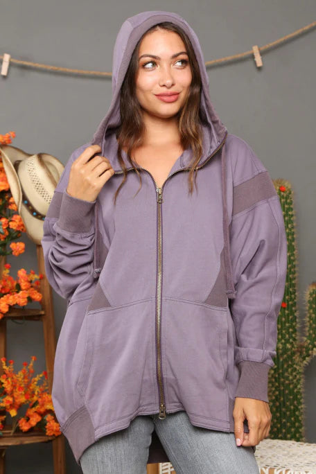 Woman wearing a purple hoodie in an indoor setting with decorative elements.