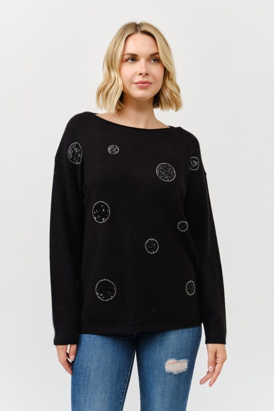Woman wearing a black sweater with circular patterns on a white background