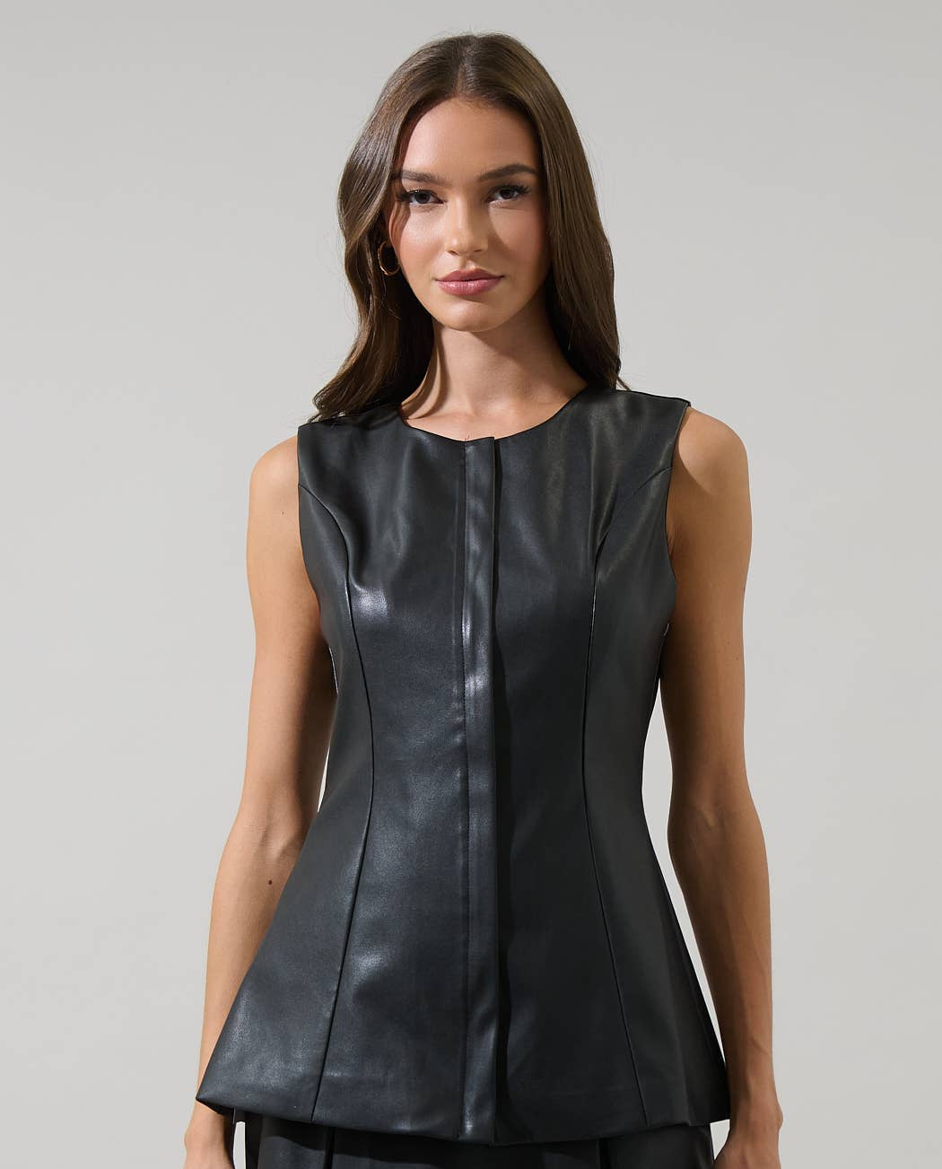 Woman wearing a black leather dress against a gray background