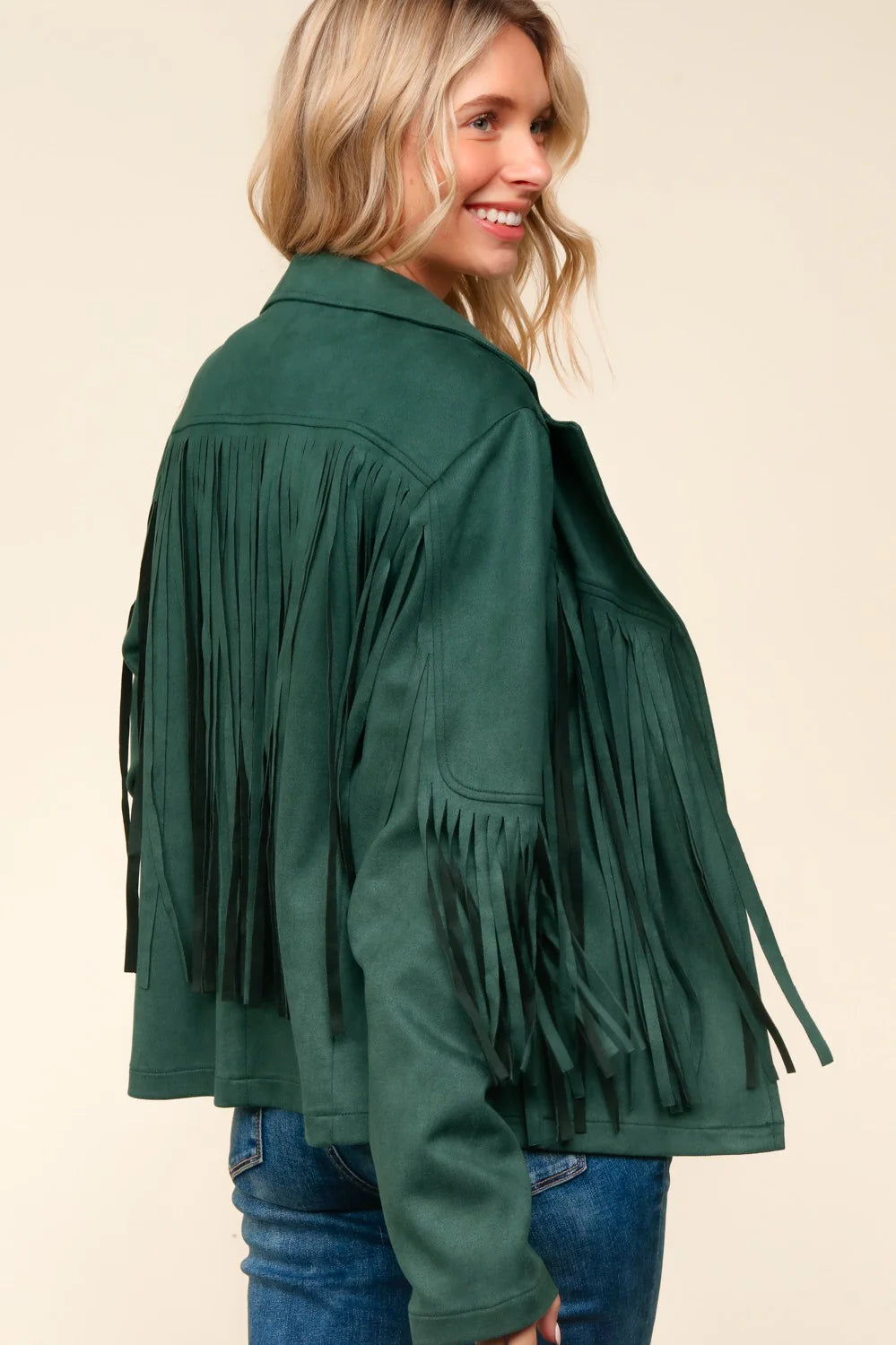 Woman wearing a green fringed jacket on a beige background
