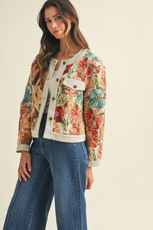 Woman wearing a floral jacket and jeans on a plain background