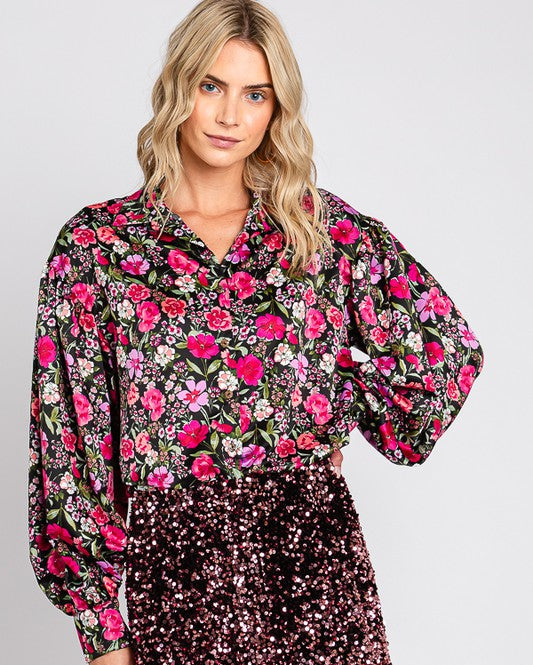 Woman wearing a floral blouse and sequin shorts on a plain background