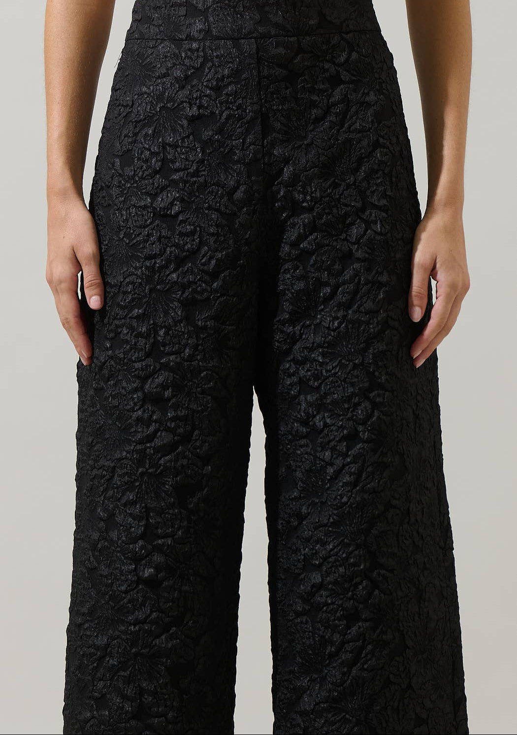 Black textured pants worn by a person on a plain background