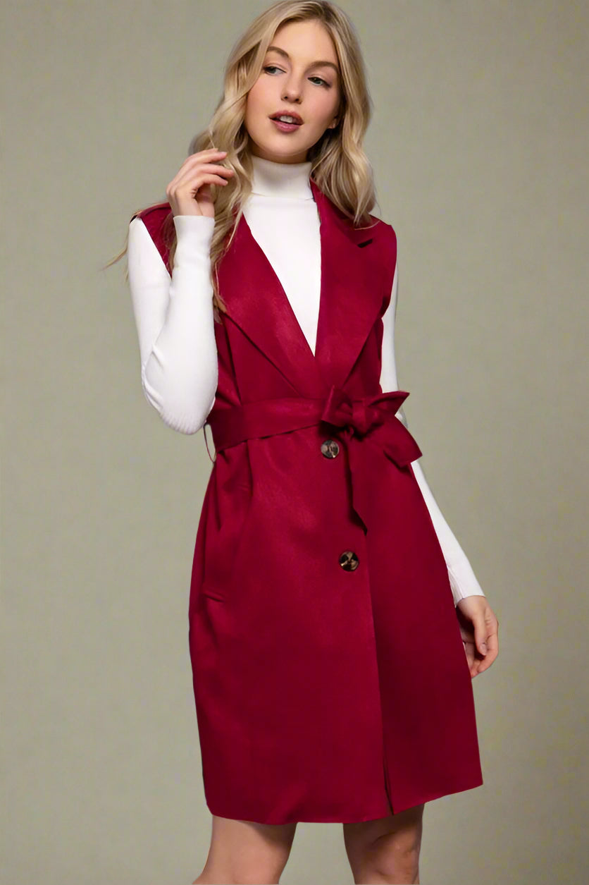 Woman wearing a red vest over a white top on a gray background