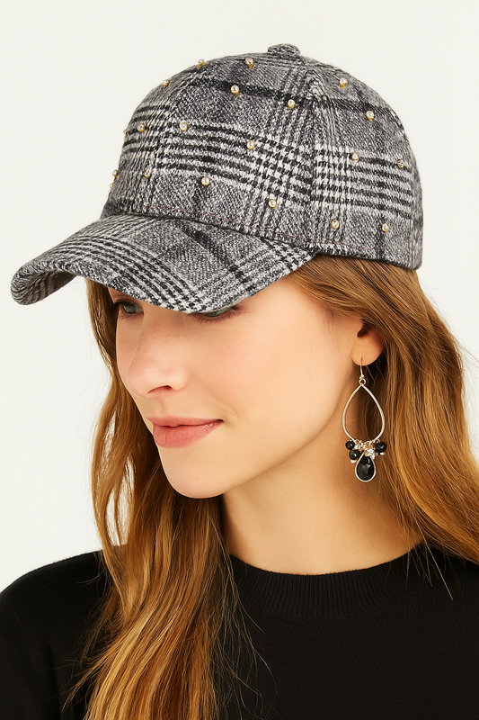 Woman wearing a plaid cap with embellishments on a white background