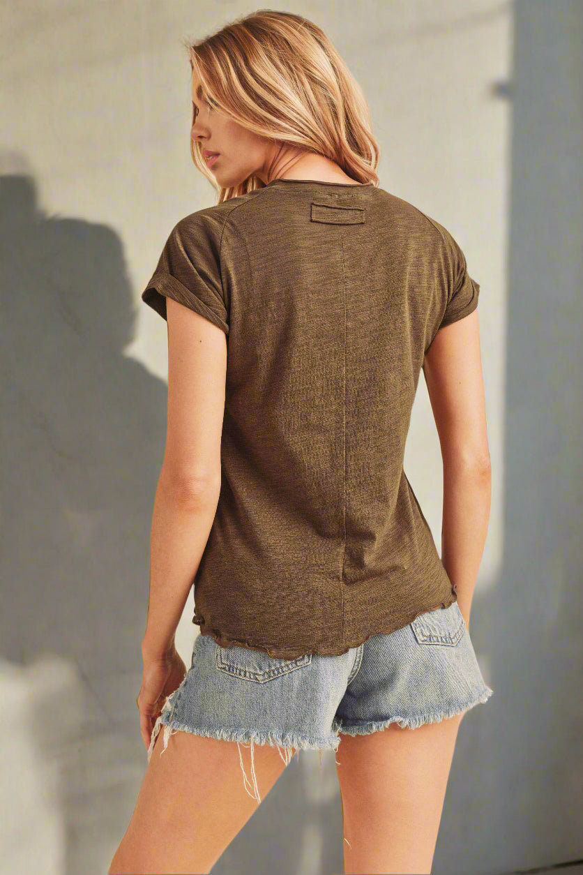 Woman wearing a green t-shirt and denim shorts on a beige background