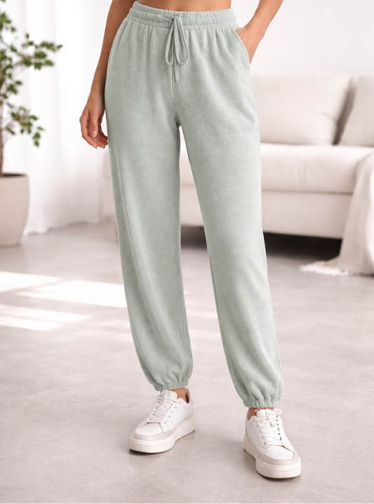 Person wearing light grey jade sweatpants and white sneakers in a room.