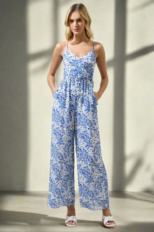 Woman wearing a blue floral jumpsuit on a plain background