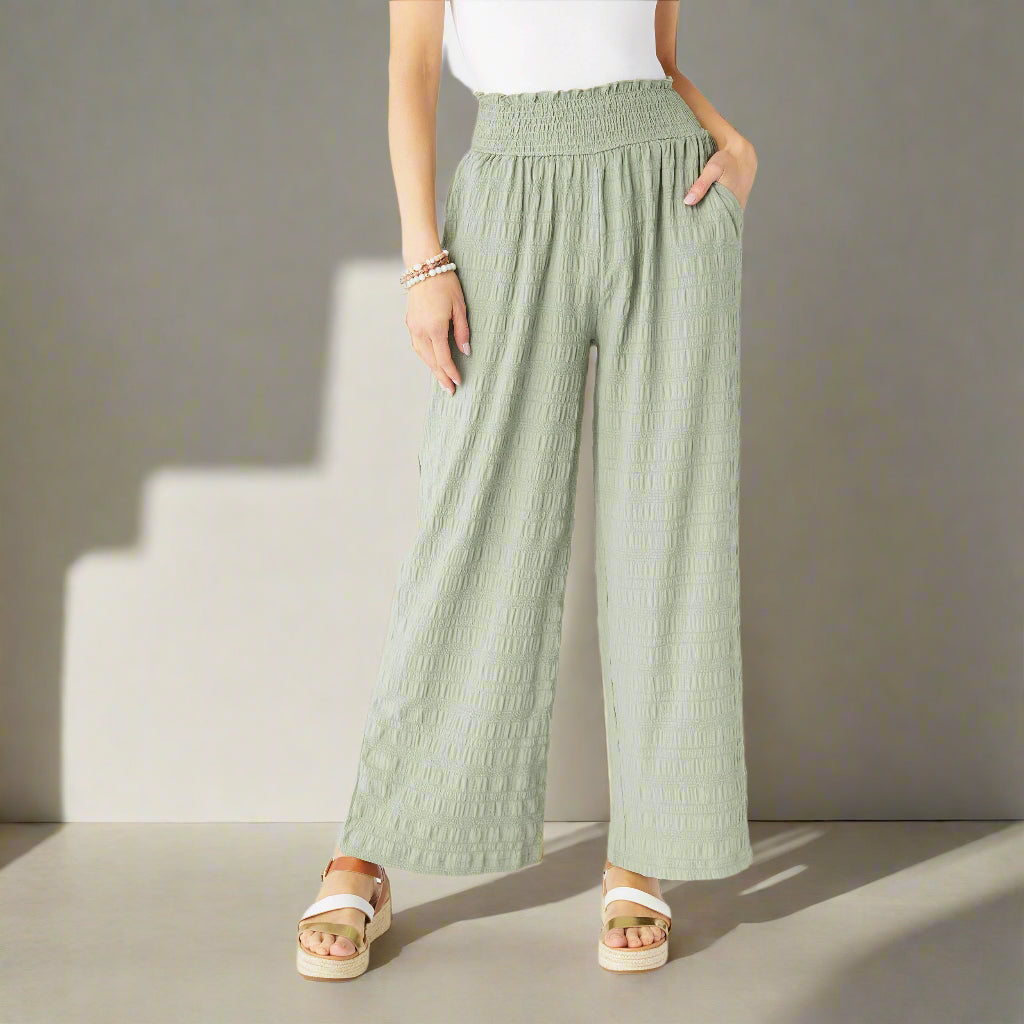 Person wearing light green wide-leg pants on a white background