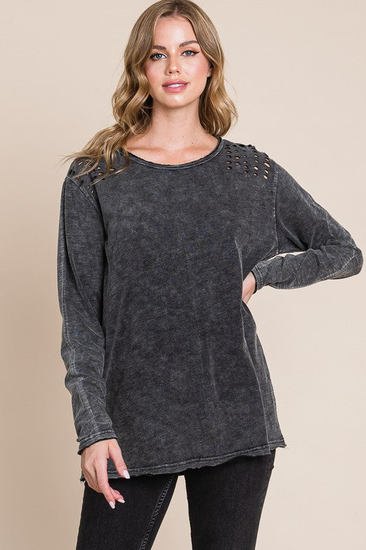 Woman wearing a grey distressed sweater on a beige background