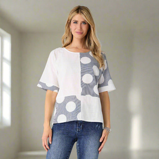 Woman wearing a polka dot blouse and jeans on a white background