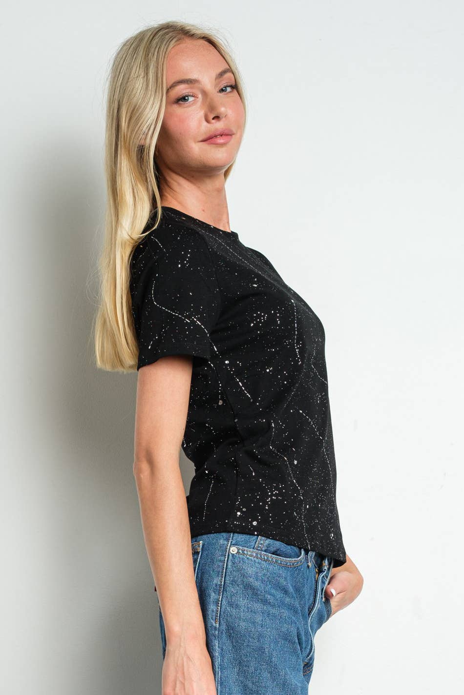 Woman wearing a black t-shirt with white patterns against a plain background