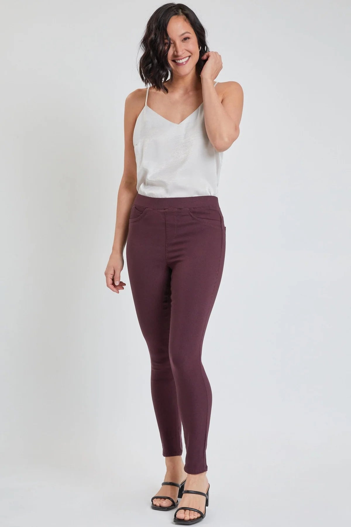 Woman wearing a white top and burgundy pants on a white background