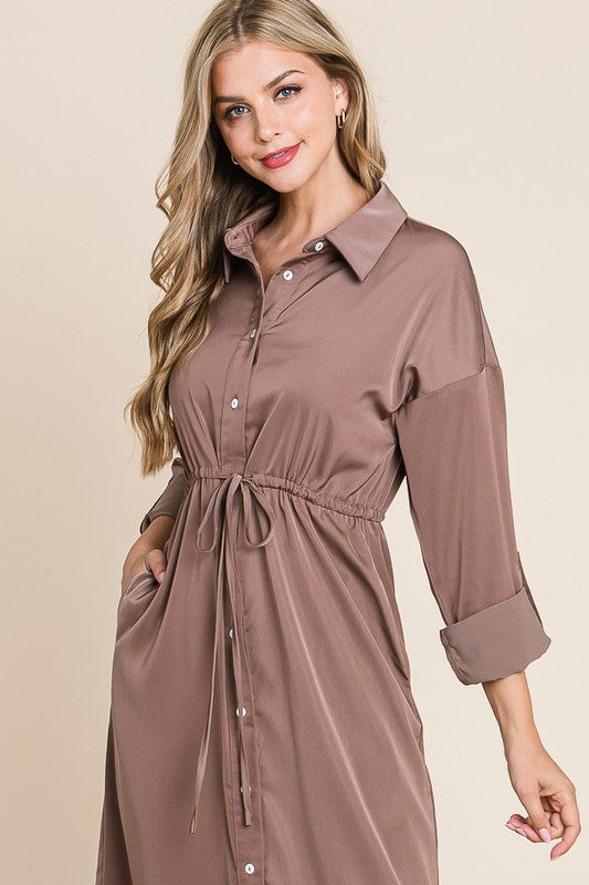 Woman wearing a brown shirt dress against a beige background