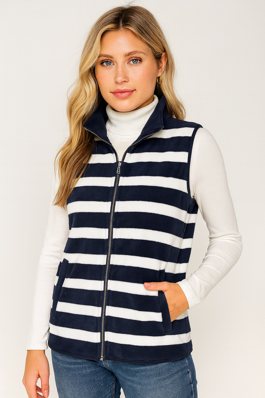 Woman wearing a navy and white striped vest over a white long-sleeve shirt on a plain background