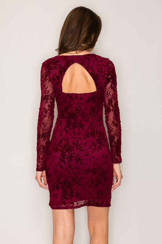 Burgundy lace dress with long sleeves and cutout back on a plain background