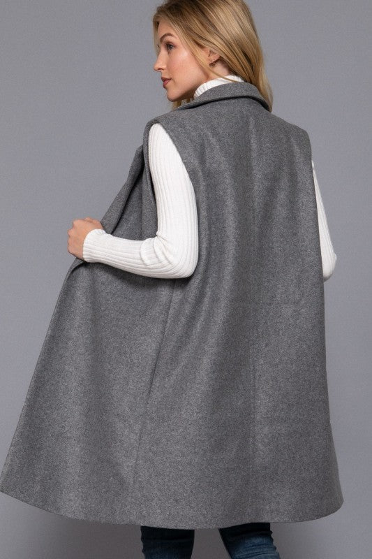 Woman wearing a gray vest over a white shirt on a gray background