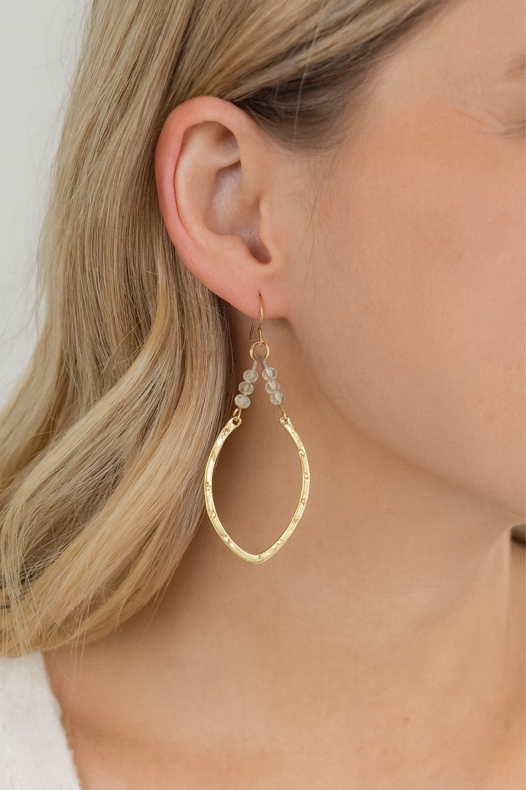 Gold hoop earrings worn by a person with blonde hair.