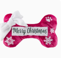 Pink bone-shaped Christmas toy with a white bow and snowflake designs on a red background
