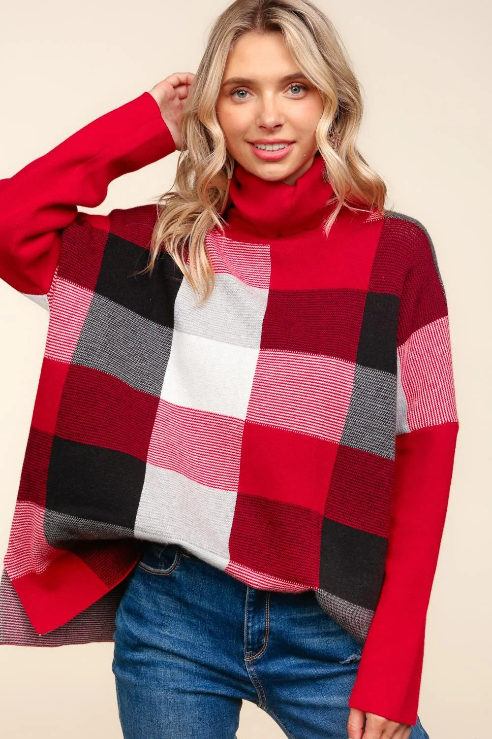 Woman wearing a red, black, and gray checkered sweater against a beige background