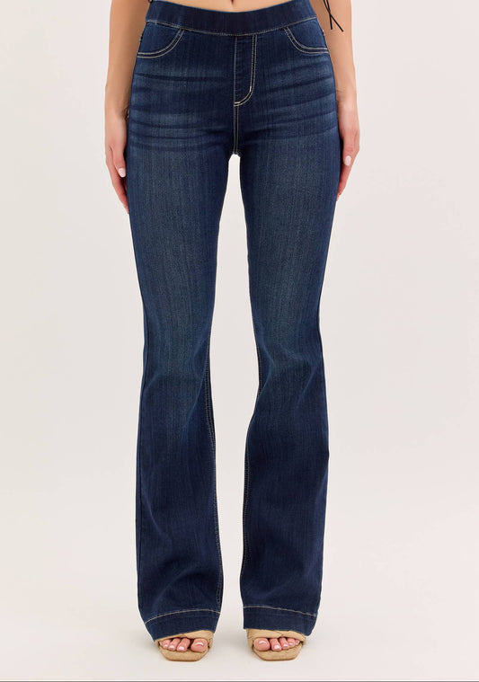 Dark blue flared jeans worn by a person on a white background