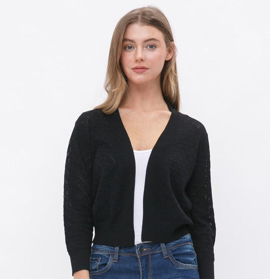 Woman wearing a black cardigan over a white top and blue jeans on a white background