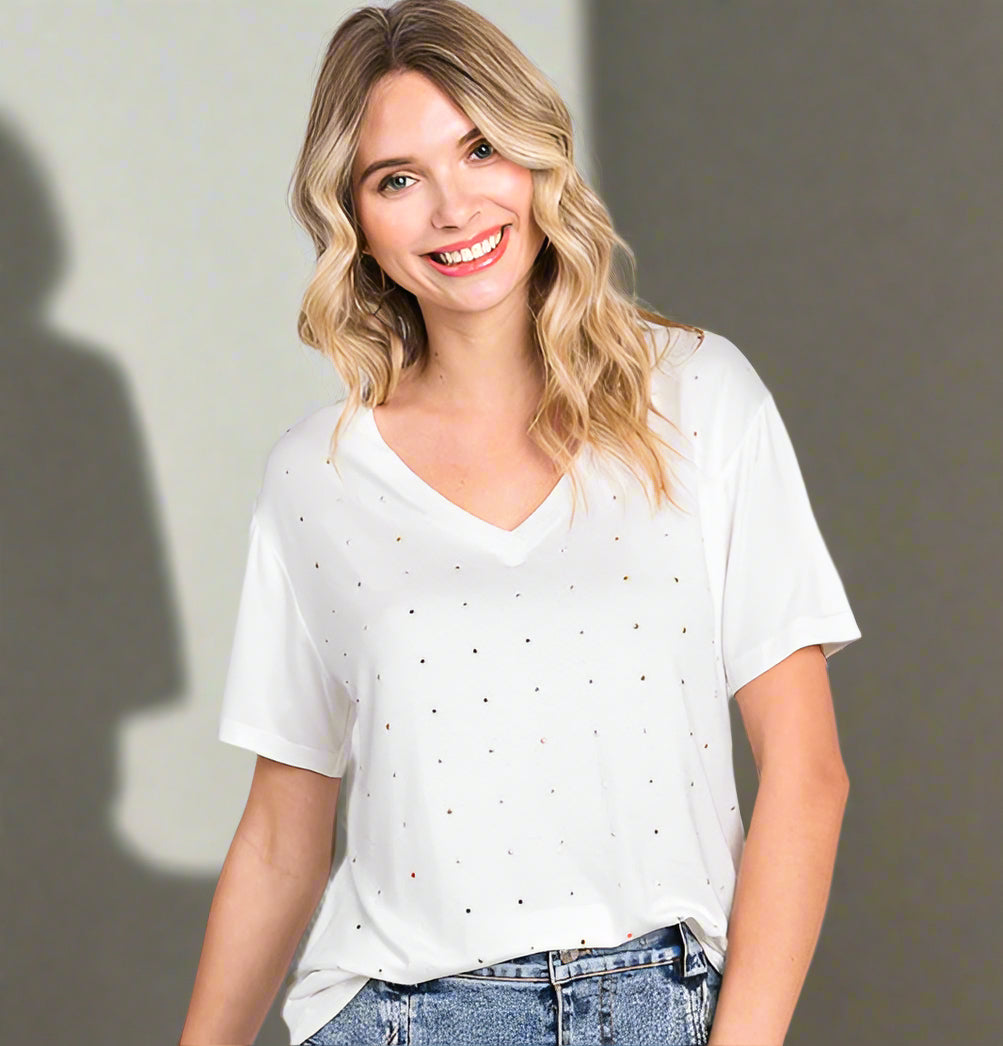 Woman wearing a white top with small black patterns and a denim skirt on a light gray background