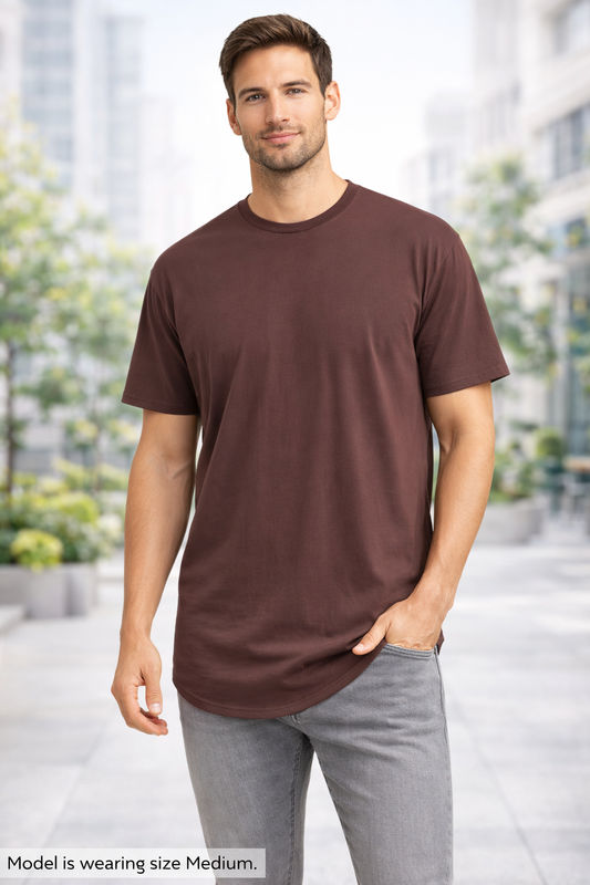 Man wearing a brown t-shirt and gray pants standing outdoors with blurred background