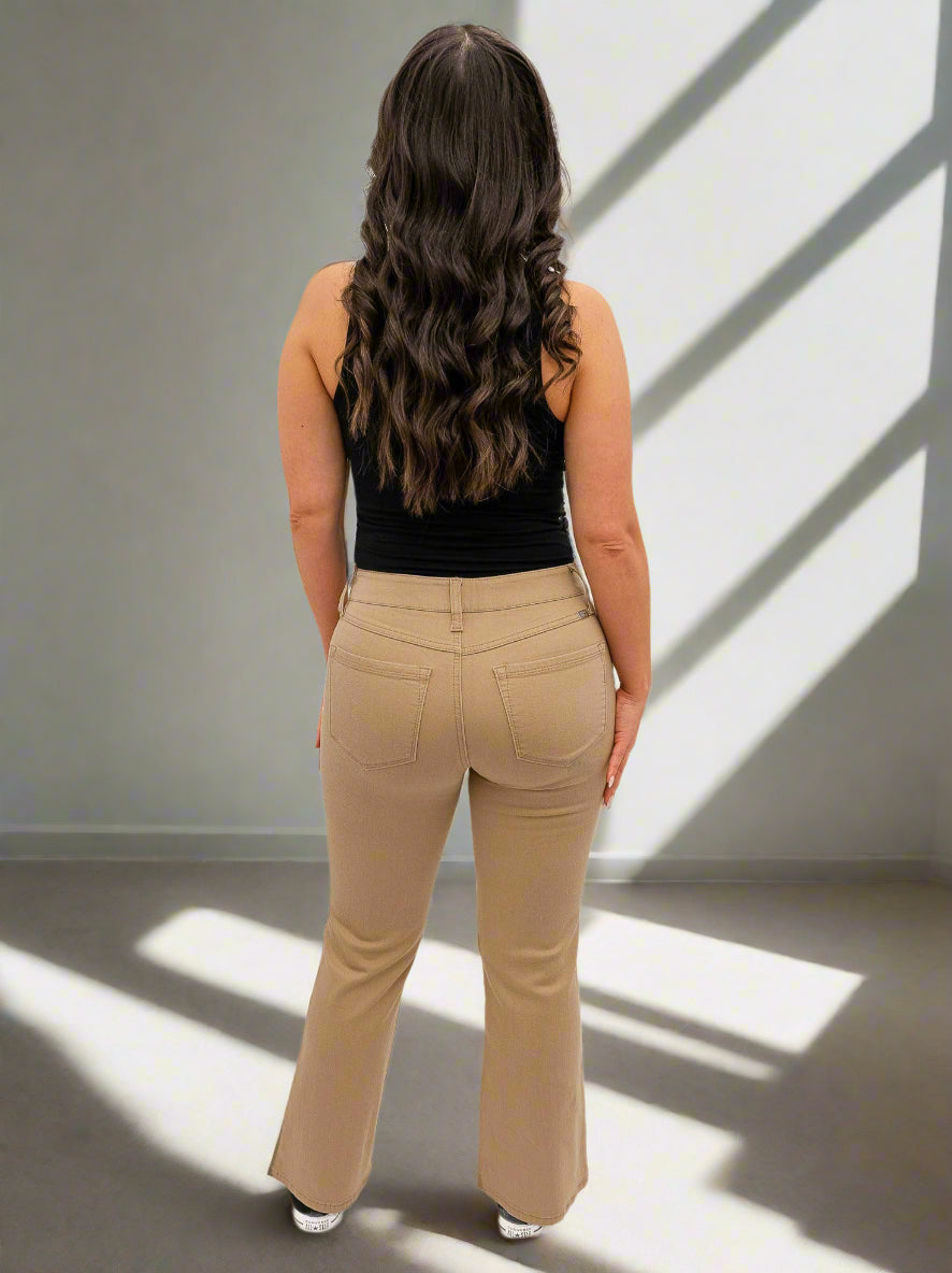 Woman wearing beige pants and a black top on a white background