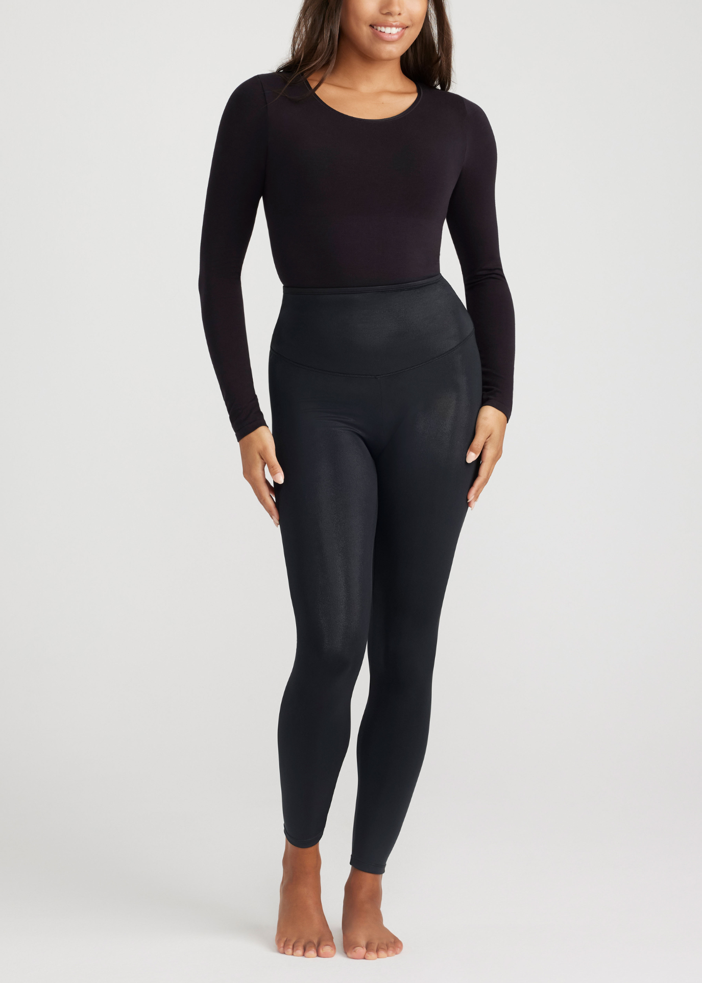 Person wearing a black long-sleeve top and leggings on a white background