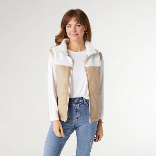 Woman wearing a white and beige fleece vest on a plain background