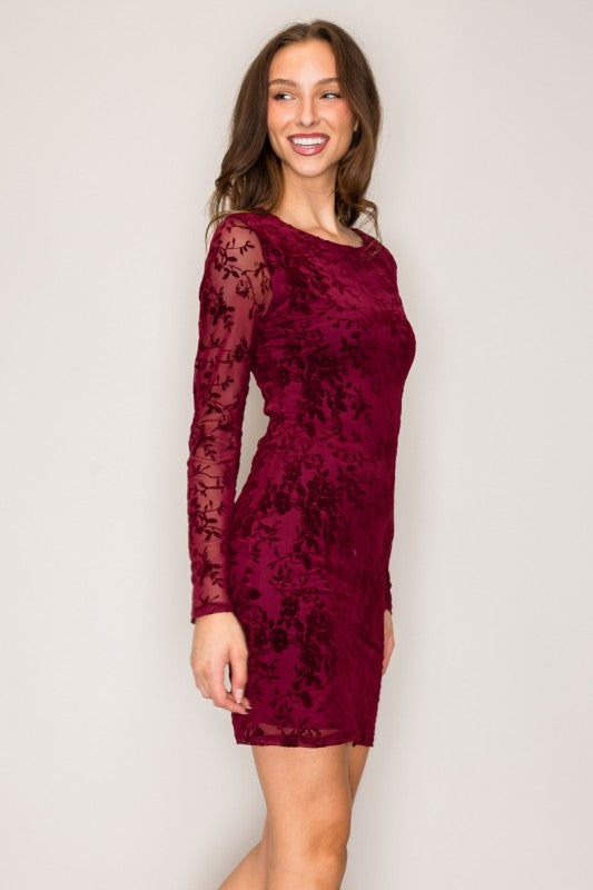 Woman wearing a burgundy lace dress against a plain background