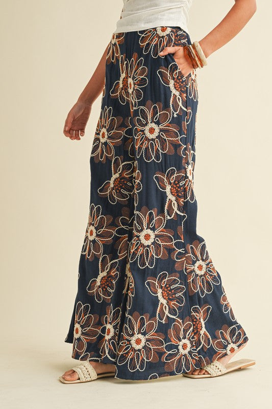 Navy floral-patterned pants worn by a person on a beige background