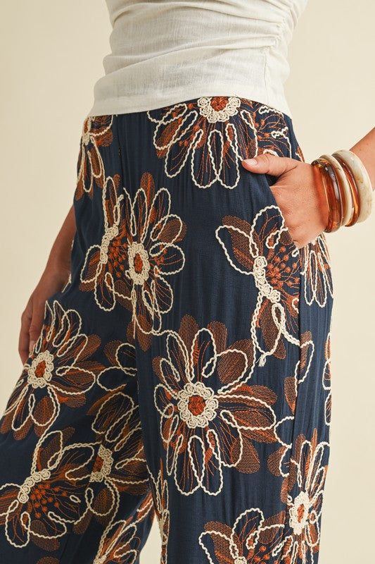Navy blue pants with brown floral patterns worn by a person.