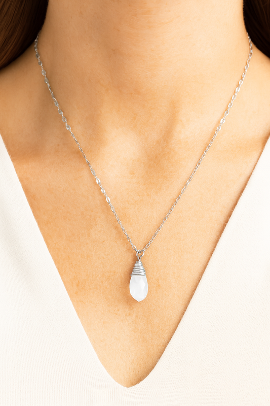 Silver teardrop necklace on a person's neck against a neutral background
